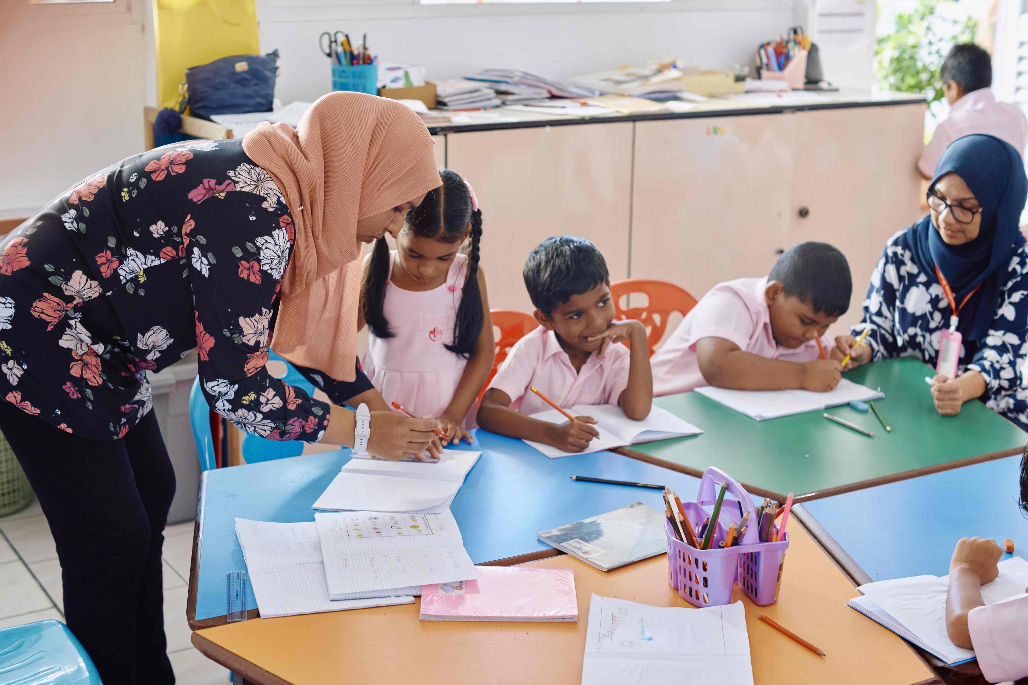 A teacher helping children with their work